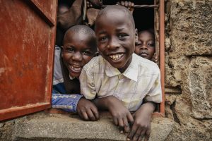 Some children in a window smiling.