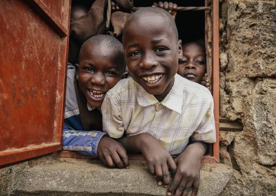 Some children in a window smiling.