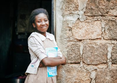 A girl smiling while leaning on a wall.