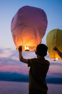 A young boy about to let go of a paper lantern.
