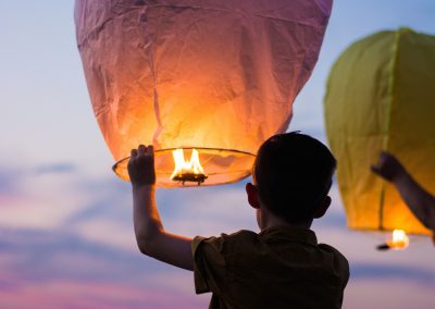 A young boy about to let go of a paper lantern.