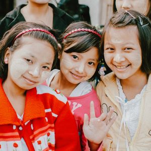 Three girls smiling and waving.