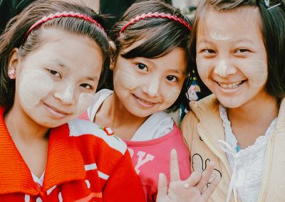 Three girls smiling and waving.