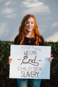 A Girl Holding a sign that says "Together We Can End Child Sex Slavery"