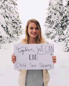 A girl holding a sign that says "Together We Can End Child Sex Slavery"