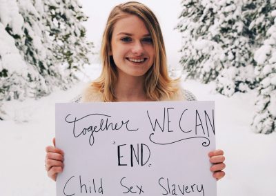 A girl holding a sign that says "Together We Can End Child Sex Slavery"