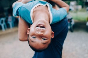 A young boy smiling while being lifted up.