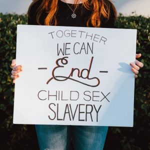 A girl holding a sign that reads "Together We Can End Child Sex Slavery"