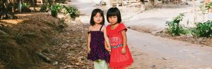 Two young girls standing in a street.